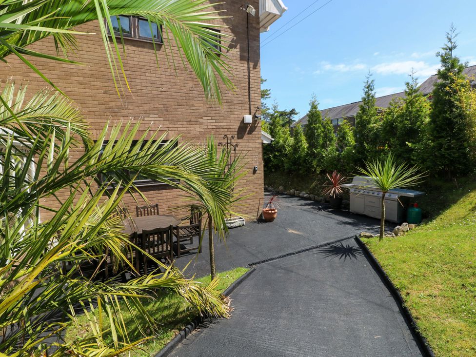 A garden with a table and chairs next to a gas grill at 170 Langland Road Mumbles
