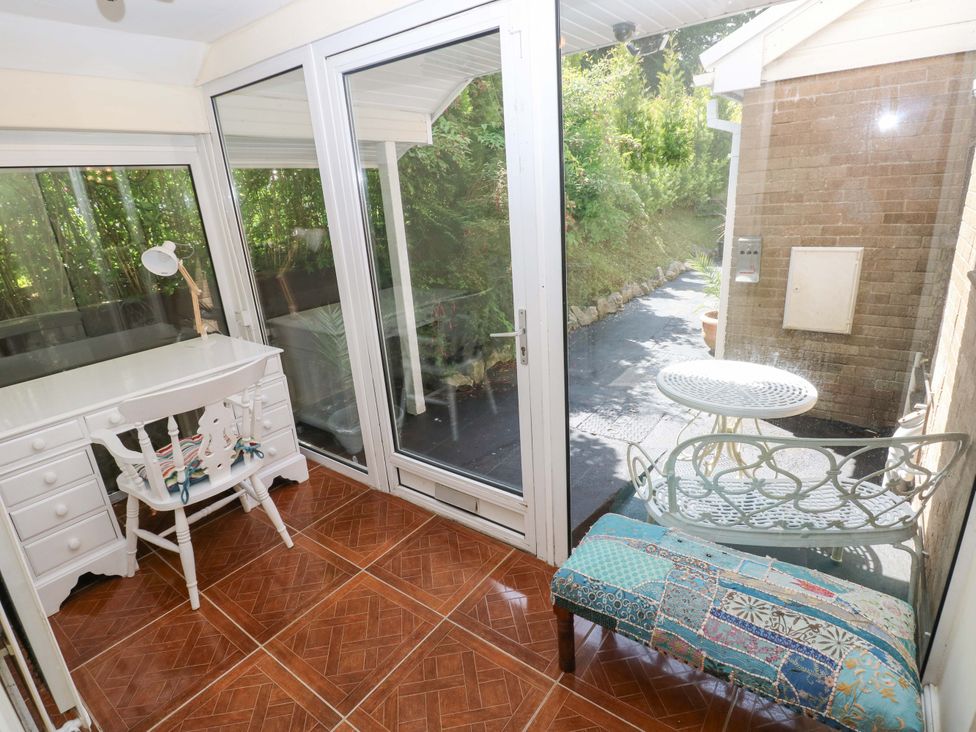 A conservatory with a desk and sofa at 170 Langland Road in Mumbles