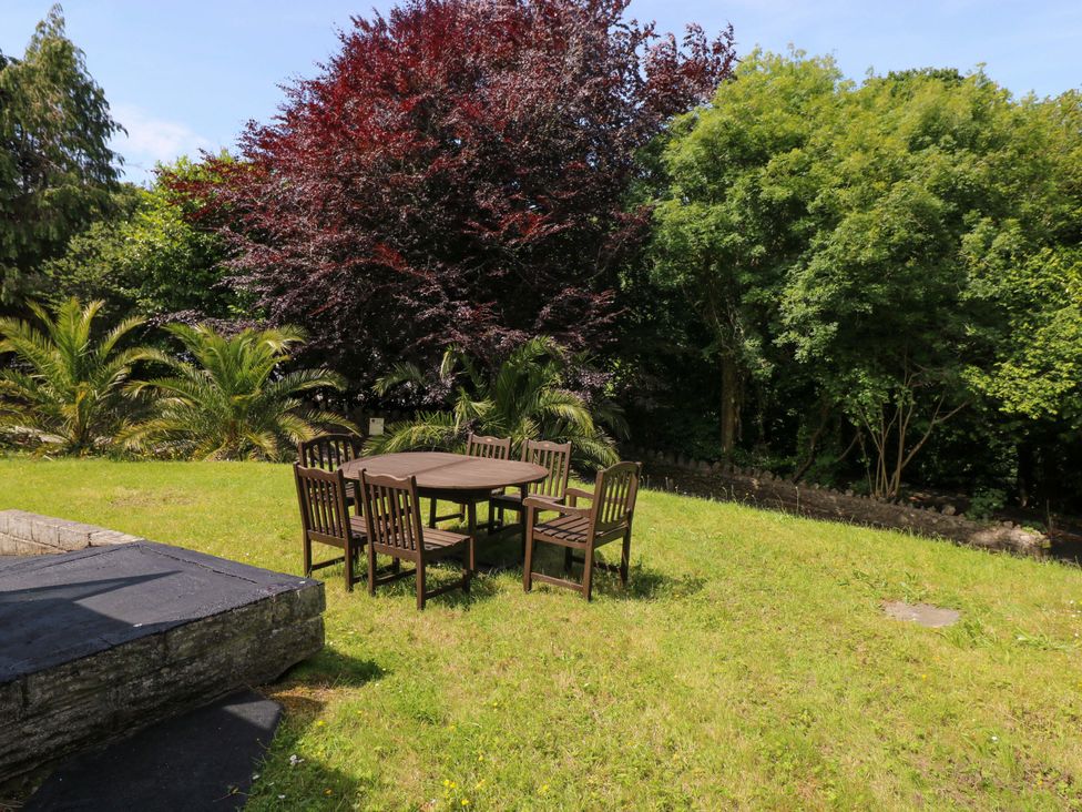 A garden with a table and chairs surrounded by trees at 170 Langland Road Mumbles