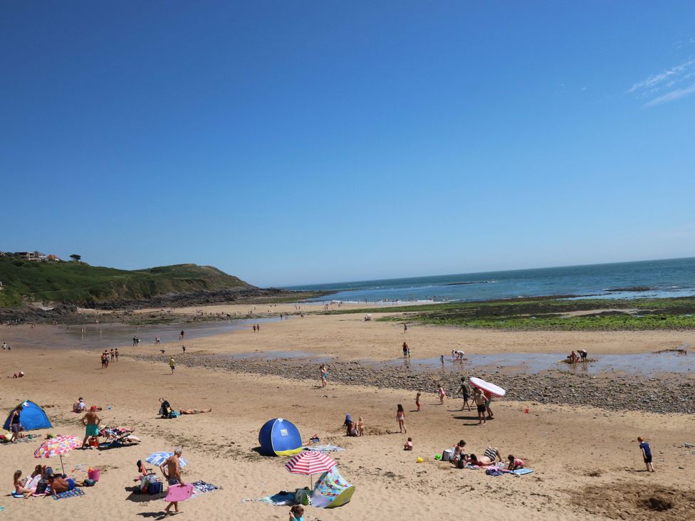 A beach with people enjoying the sun and playing on the sand near the ocean at 170 Langland Road Mumbles