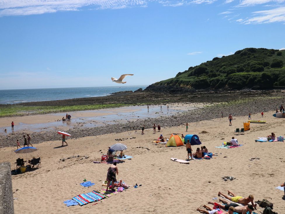 A beach scene with people, umbrellas, and towels at 170 Langland Road in Mumbles