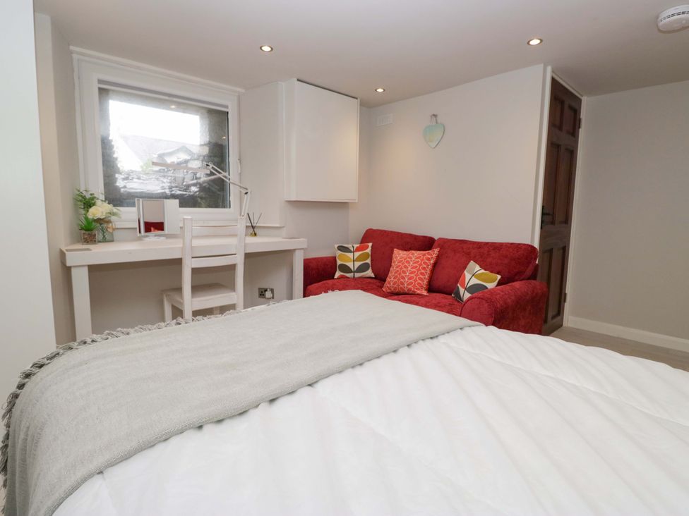 A bedroom with a bed, desk, and sofa at Poppy Cottage in Bowness-On-Windermere