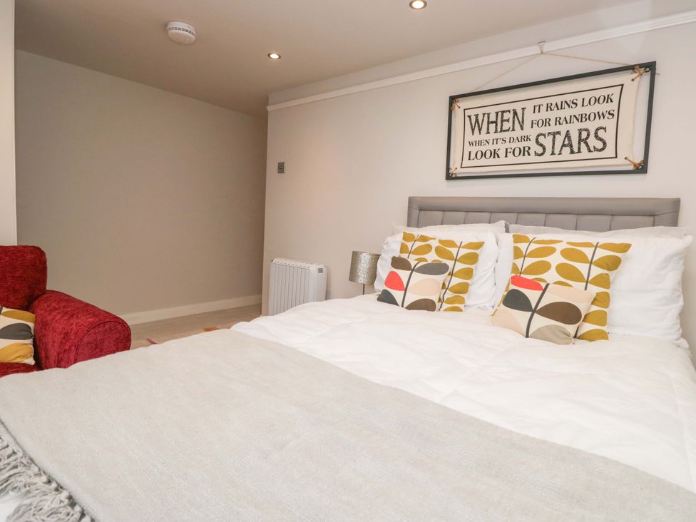 A bedroom with a bed and armchair at Poppy Cottage in Bowness-On-Windermere