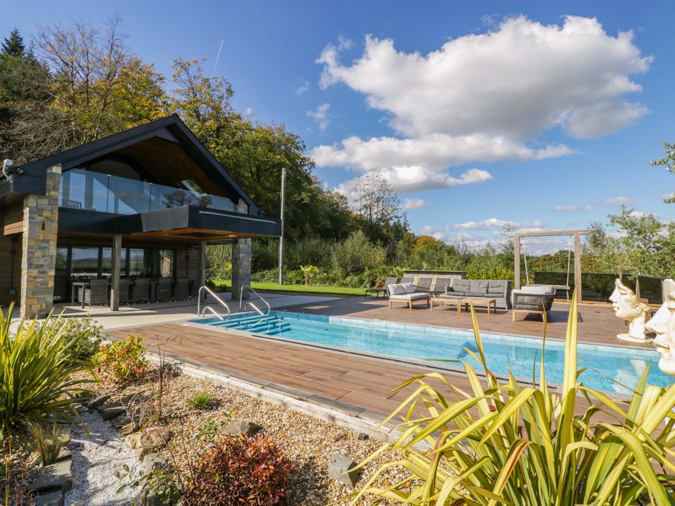 An outdoor area with a swimming pool and seating at Forest Lodge Pontyclun