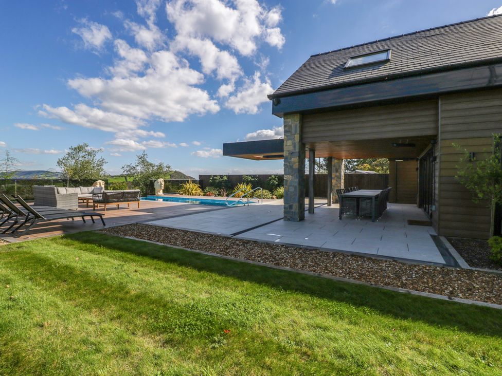 An outdoor area with a swimming pool and seating at Forest Lodge in Pontyclun