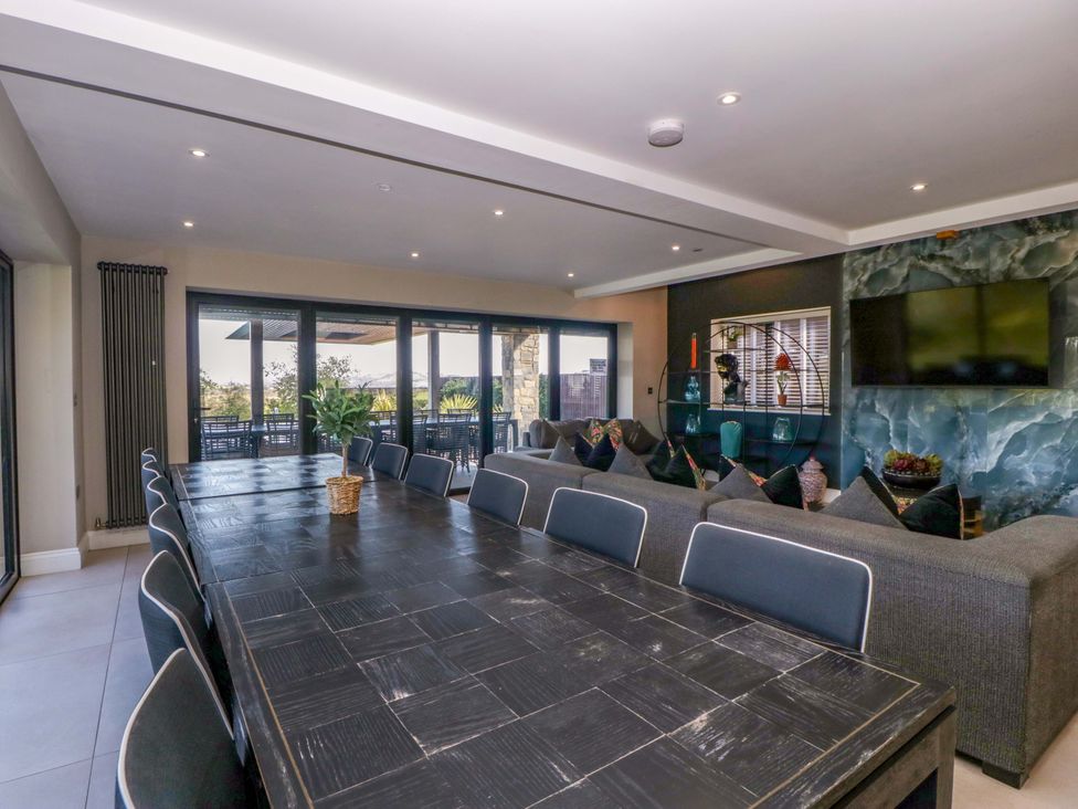 A dining room with a large table and sofa at Forest Lodge in Pontyclun