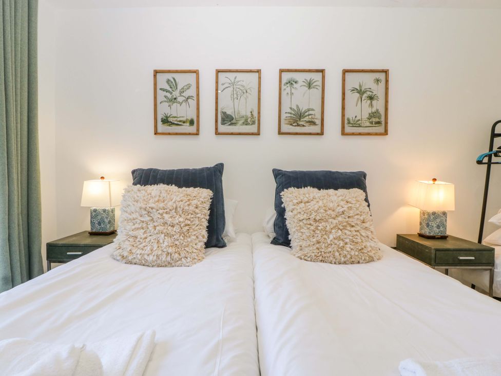 A bedroom with two beds and framed artwork at Forest Lodge in Pontyclun