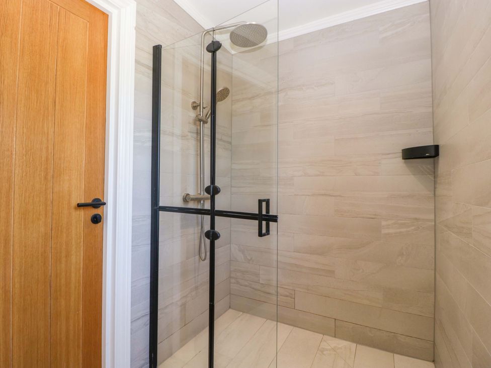 A shower with glass door and wall tiles at Forest Lodge in Pontyclun