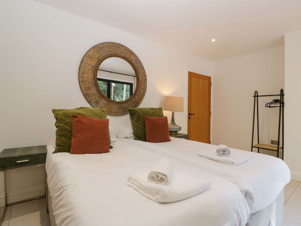 A bedroom with two beds and a lamp at Forest Lodge Pontyclun