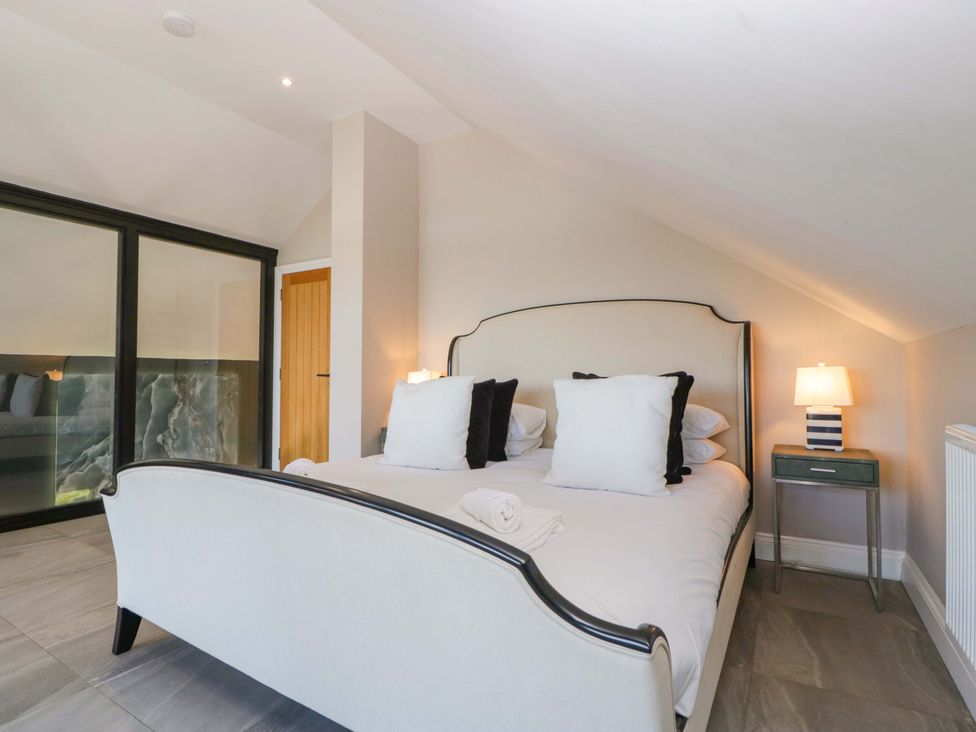 A bedroom with a bed and nightstand at Forest Lodge in Pontyclun