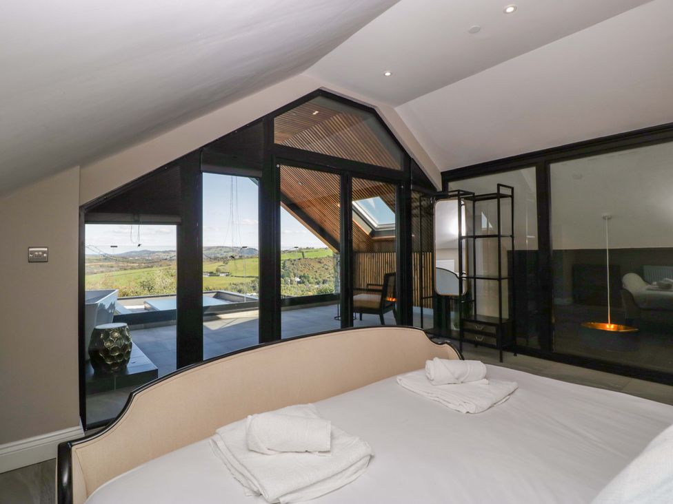 A bedroom with a bed and view outside at Forest Lodge in Pontyclun