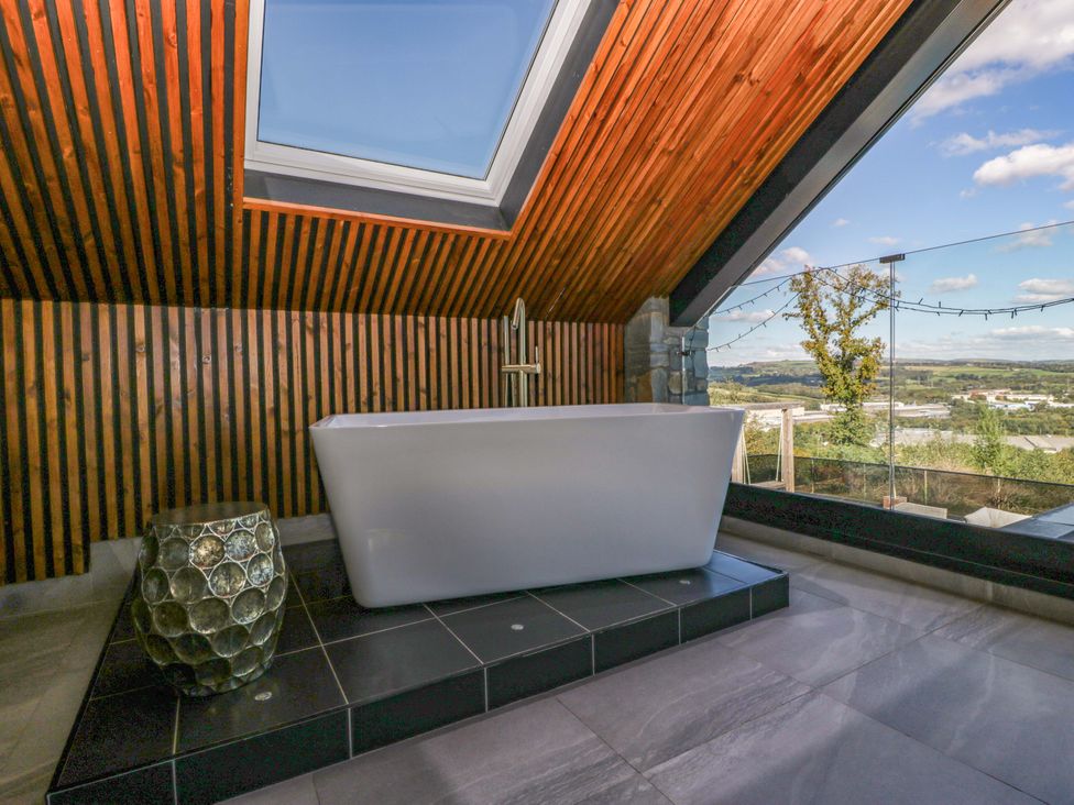 A bathroom with a bathtub and skylight at Forest Lodge in Pontyclun