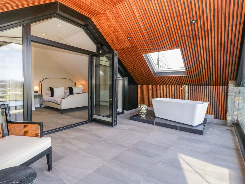A bedroom with a bath and a bed at Forest Lodge Pontyclun