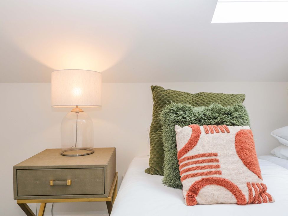A bedroom with a lamp and pillows on a nightstand at Forest Lodge in Pontyclun