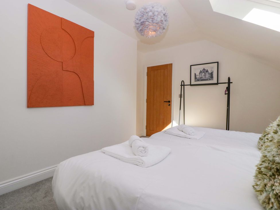 A bedroom with a bed, towels, and a painting at Forest Lodge in Pontyclun