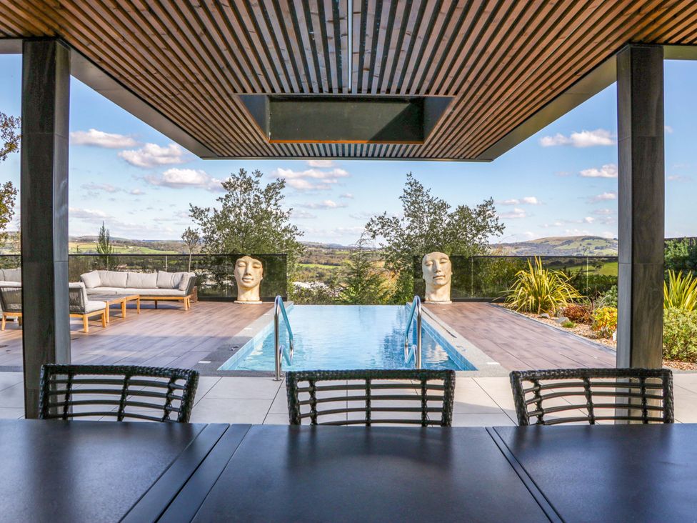An outdoor area with a swimming pool and seating at Forest Lodge in Pontyclun