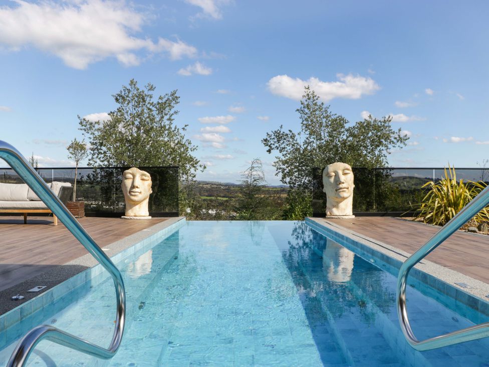 A swimming pool with sculptures and a seating area at Forest Lodge in Pontyclun