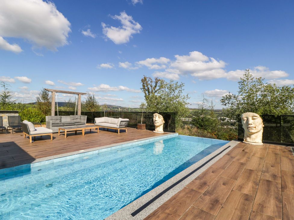 An outdoor area with a swimming pool and seating at Forest Lodge in Pontyclun