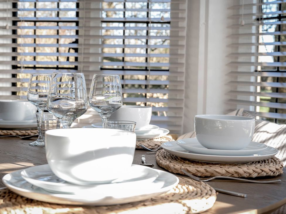 A dining table set with plates and glasses at East Lodge in Peterborough