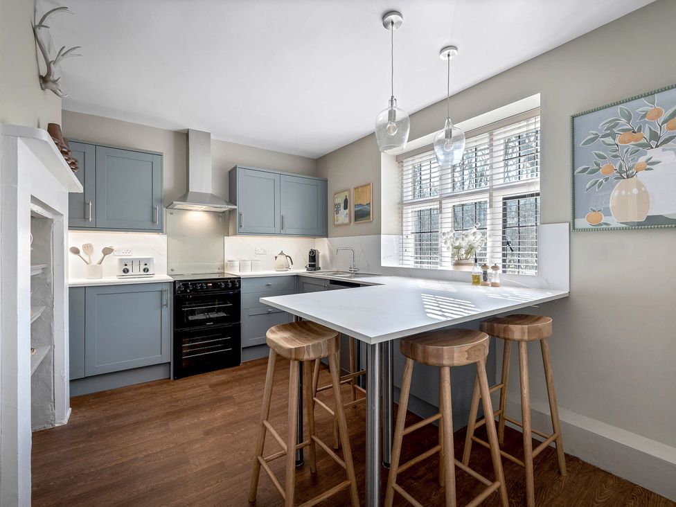 A kitchen with cabinets and bar stools at East Lodge in Peterborough