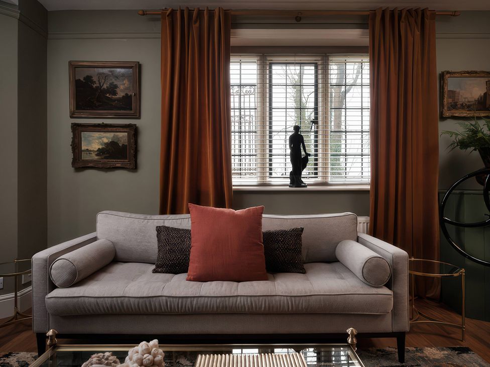 A living room with a sofa and paintings at The Gatehouse in Peterborough