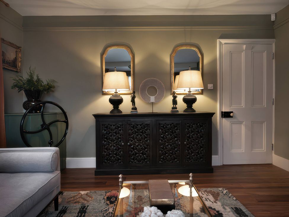 A living room with mirrors and lamps on a sideboard at The Gatehouse in Peterborough