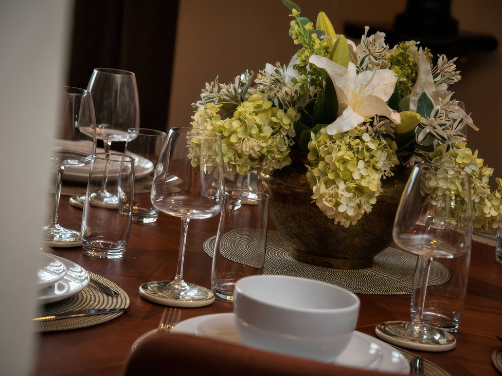 A dining table set with glasses and a flower arrangement at The Gatehouse in Peterborough