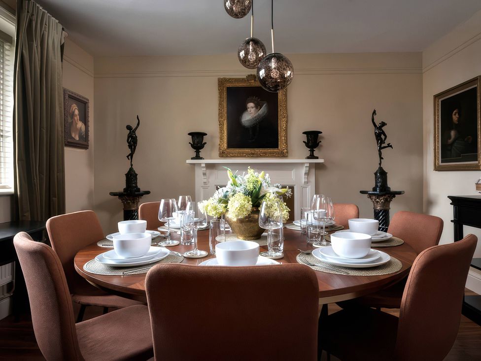 A dining room with a round table set for dinner at The Gatehouse in Peterborough
