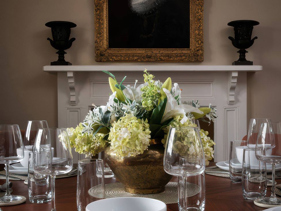 A dining room with a floral arrangement on the table at The Gatehouse in Peterborough