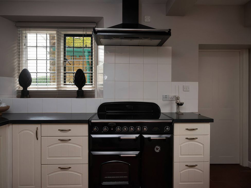 A kitchen with white cabinets and a black stove at The Gatehouse in Peterborough