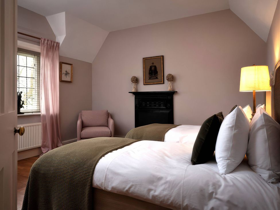 A bedroom with two beds and an armchair at The Gatehouse in Peterborough