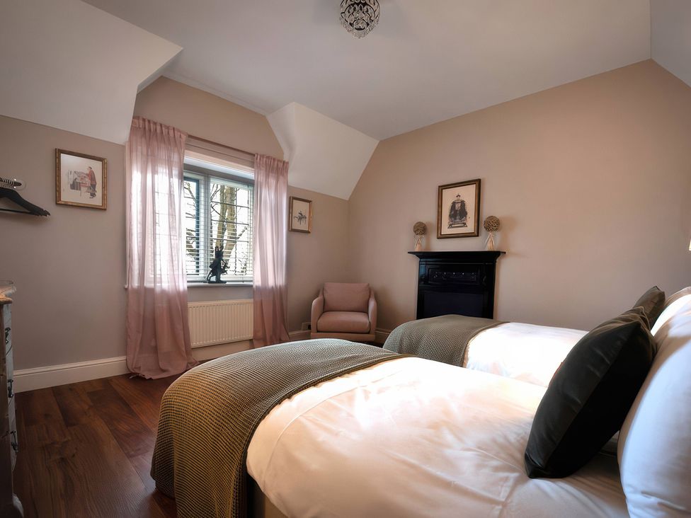 A bedroom with two beds and a chair at The Gatehouse in Peterborough