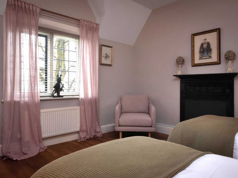 A bedroom with two beds and an armchair at The Gatehouse in Peterborough