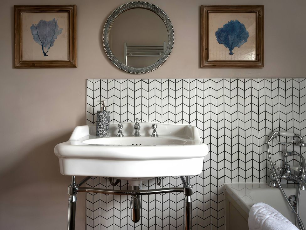 A sink with a mirror and wall decor at The Gatehouse in Peterborough
