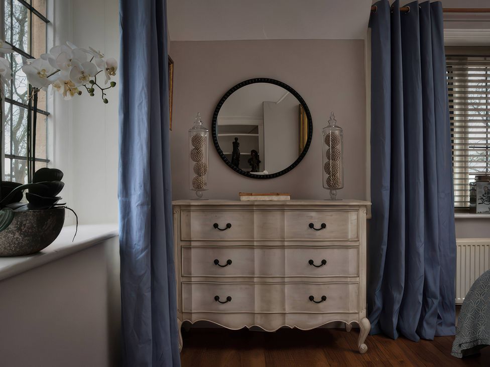 A bedroom with a dresser and mirror at The Gatehouse in Peterborough