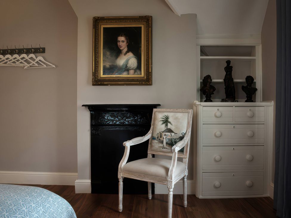 A bedroom with a chair and a portrait on the wall at The Gatehouse in Peterborough