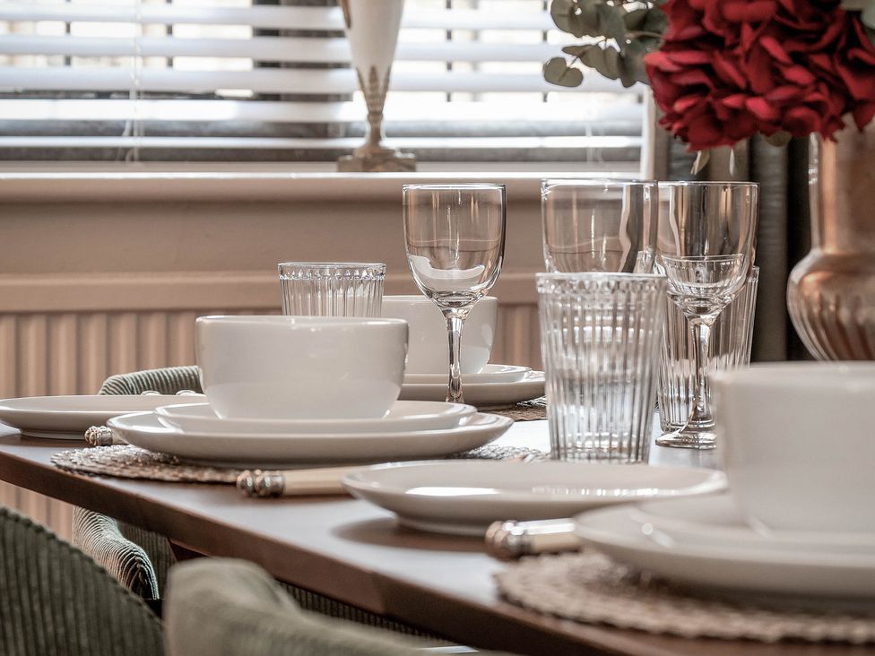 A dining room table set with plates and glasses at Raphael Rooms in Peterborough