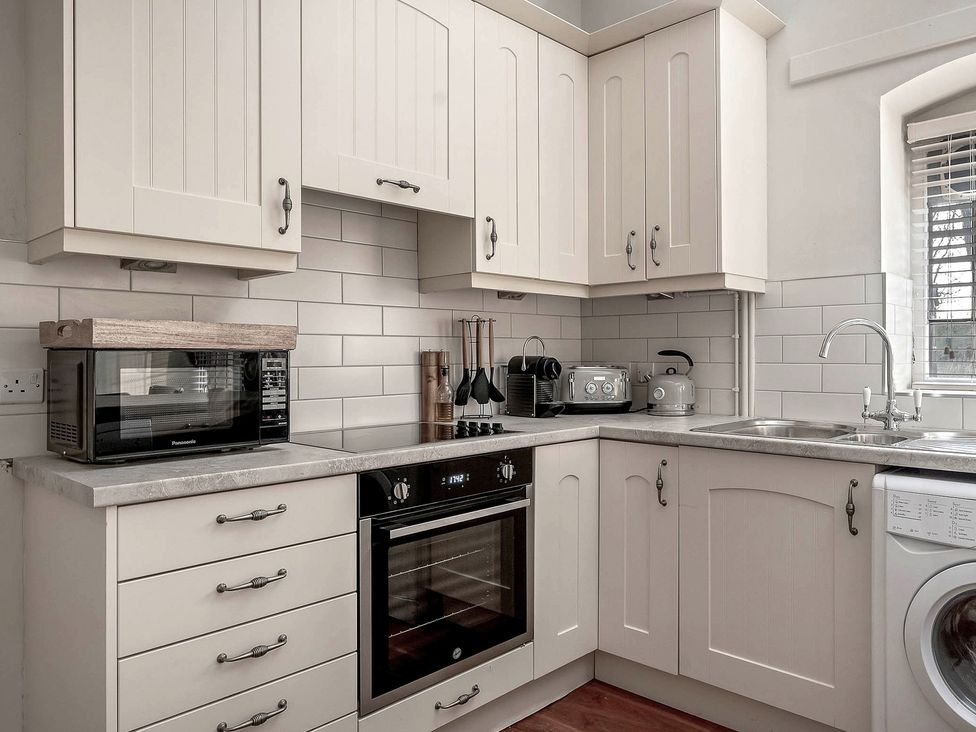 A kitchen with appliances and cabinets at Raphael Rooms in Peterborough
