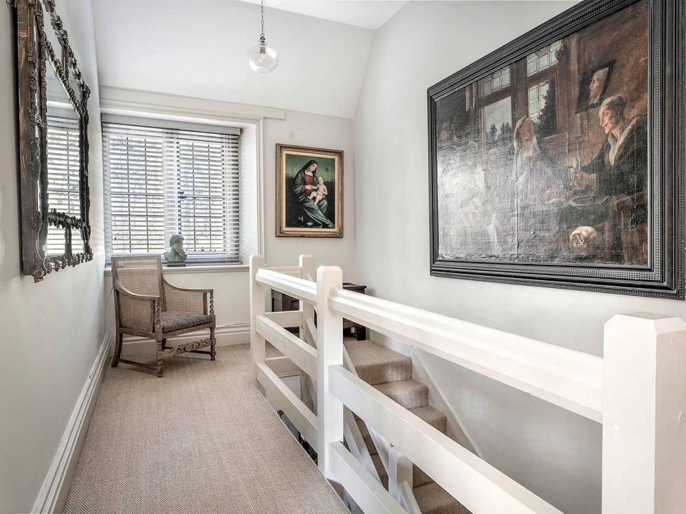 A hallway with a chair and paintings at Raphael Rooms in Peterborough