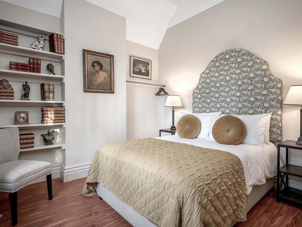 A bedroom with a bed and bookshelf at Raphael Rooms in Peterborough