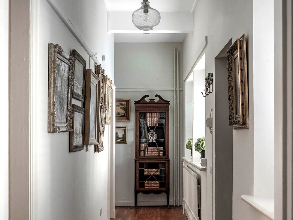 A hallway with decorative frames and a sideboard at Raphael Rooms in Peterborough