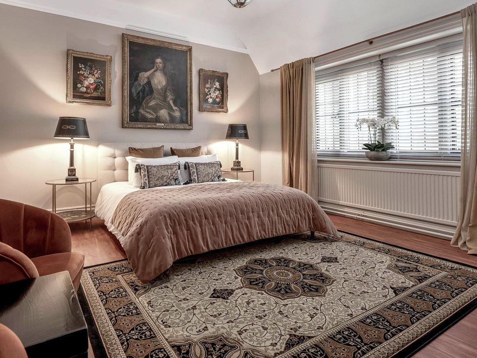 A bedroom with a bed and paintings at Raphael Rooms Peterborough