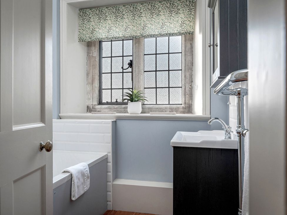 A bathroom with a bathtub and window at Raphael Rooms in Peterborough