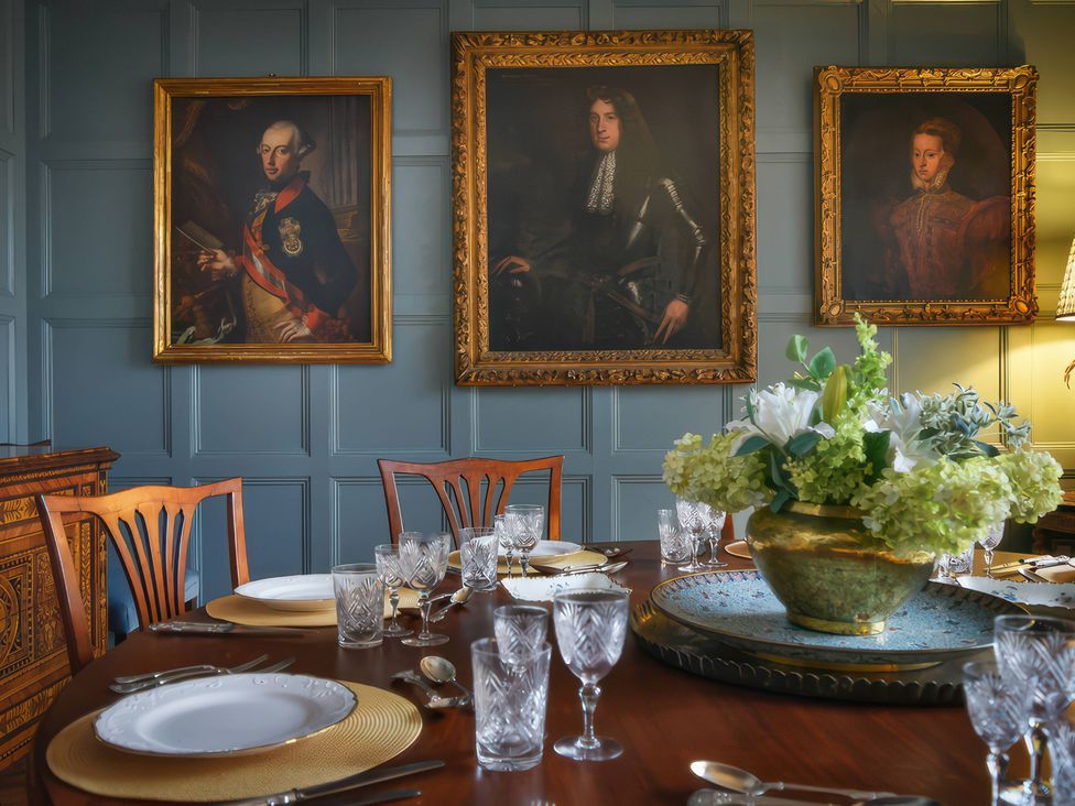 A dining room with a table set for dinner and paintings on the wall at Morland Manor in Peterborough