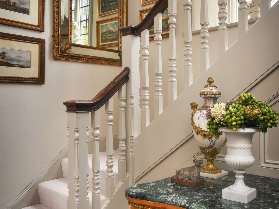 A staircase with a decorative vase and mirror at Morland Manor in Peterborough