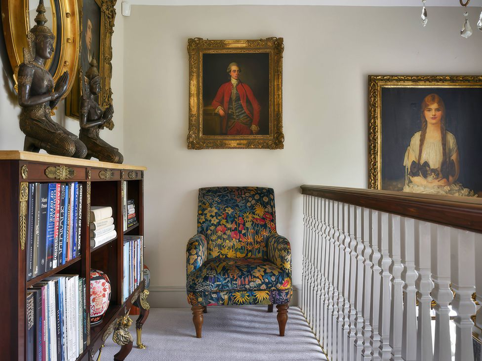 A hallway with a chair and bookshelf at Morland Manor in Peterborough
