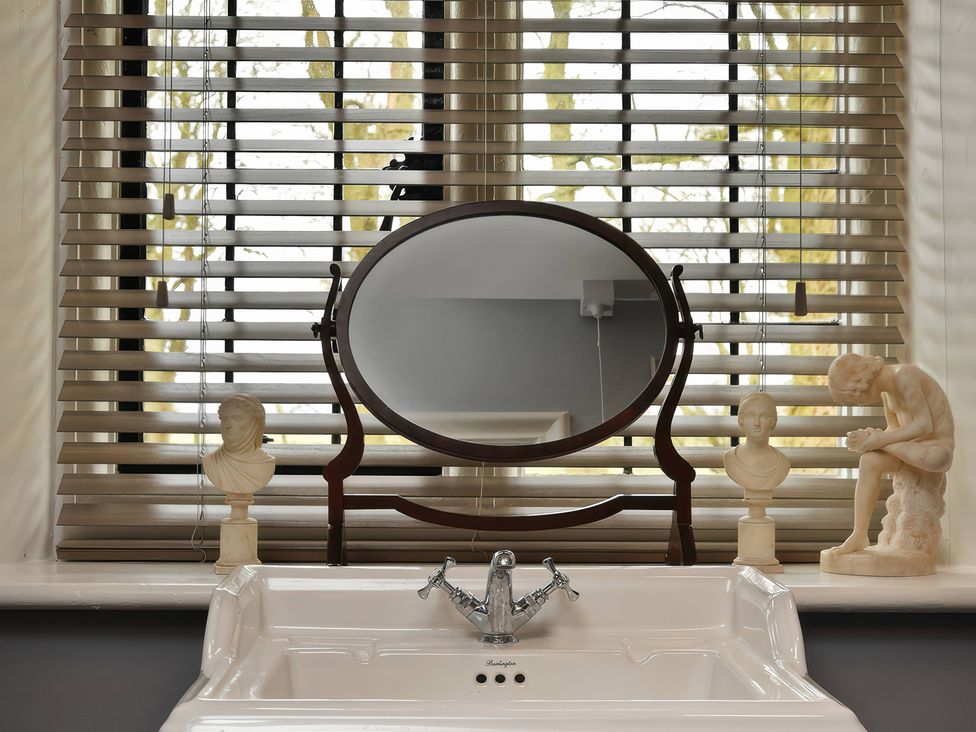 A sink with a mirror and decorative busts at Morland Manor in Peterborough