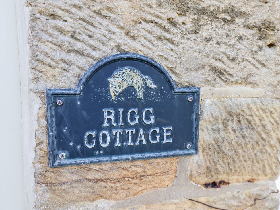 A nameplate for Rigg Cottage on a stone wall