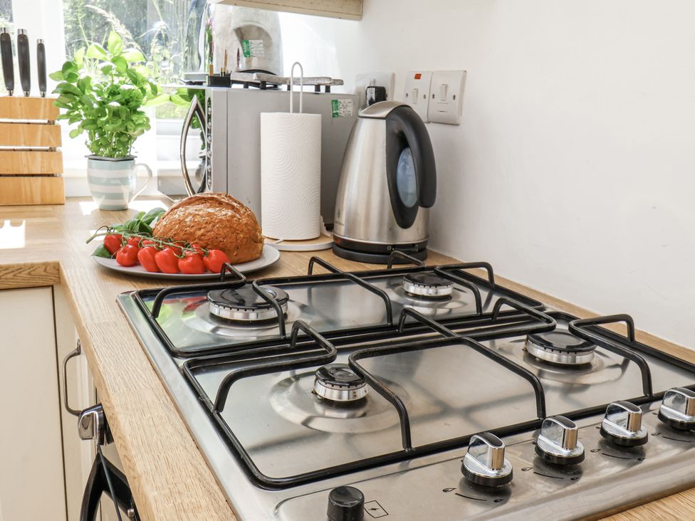 A kitchen with a gas stove and a plate of bread and tomatoes at Rigg Cottage in Sandsend