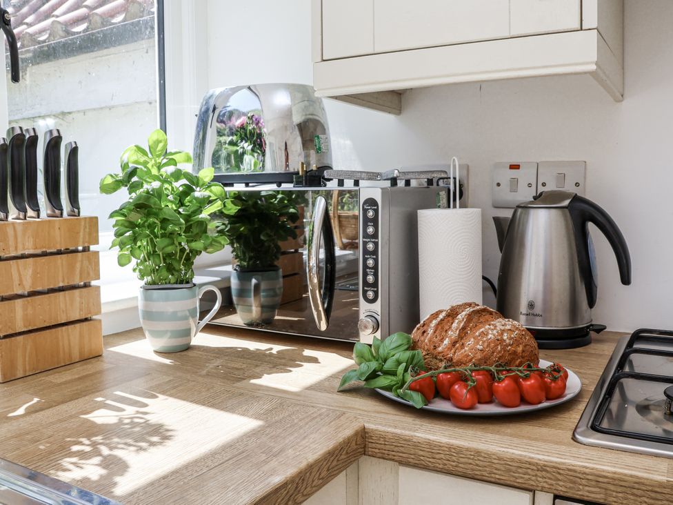 A kitchen with a toaster, kettle, and food items at Rigg Cottage in Sandsend